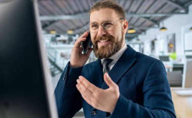 Bilgisayarlı adam cep telefonundan konuşuyor.