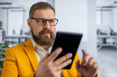 Ofiste tablet kullanan şık bir adam.