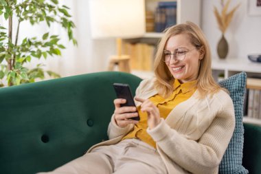 Evde akıllı telefon kullanan bir kadın.