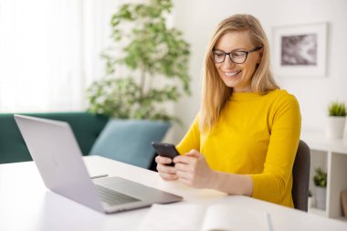 Dizüstü bilgisayar ve cep telefonu kullanan kadın