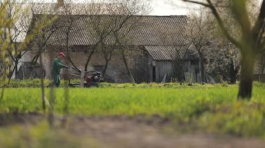 Motorlu ekiciyle toprağı süren adam.