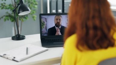 Modern ofiste sakallı CEO 'yla internet üzerinden iş görüşmesi yapan kadın ofis çalışanlarına bakıyorum. Çekici kadın dizüstü bilgisayarın önünde oturuyor ve bilgisayardaki video görüşmesi sırasında soruları cevaplıyor..