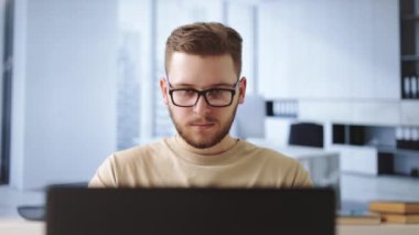 Modern ofiste dijital dizüstü bilgisayara odaklanmış erkek programcı. Yeni projesi için günlük kıyafet giyen beyaz bir genç adam görevlerini yerine getiriyor..