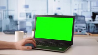 Genç profesyonel girişimci yeşil ekranlı kablosuz laptop üzerinde çalışıyor. Masanın üzerinde duran portatif bilgisayarda dokunmatik dokunmatik dokunmatik dokunun erkek parmaklarını kapat.