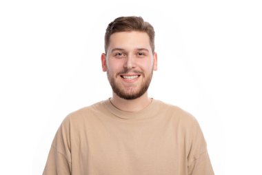 Happy caucasian male with bristle in stylish sweater standing indoors with sincere smile. Portrait of young joyful man expressing positive emotions in studio.