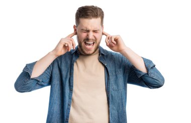 Kulaklarını parmaklarıyla kapatıp beyaz arka plana yaslanırken çığlık atan kızgın adam. Gürültülü sesleri dinlemekten rahatsız olan genç adam..