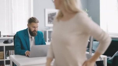 Caucasian man and women using laptop while brainstorming together at office. Team of managers considering new project plan at workplace.
