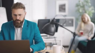 Experienced male employee checking project progress while working from cozy business center. Handsome man using online resources on modern digital laptop.