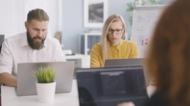 Dizüstü bilgisayarlı iş ortakları yeni çağdaş uygulama projesi hakkında konuşuyorlar. Kafkasyalı meslektaşlar parlak modern ofiste çalışma programını tartışıyor ve planlıyorlar.