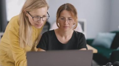 Profesyonel bayan yöneticiler konuşuyor ve ofisteki dizüstü bilgisayarları işaret ediyorlar. Kafkas iş arkadaşları çalışma planının yapısını tartışıyor..