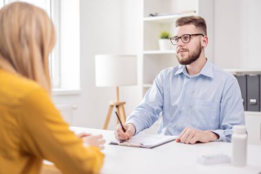 At the doctors office. Young handsome doctor psychologist talking to a female client. High quality photo