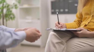 Psikolog kadın notlar alıyor, sabırlı adam, yüz resmi yok.