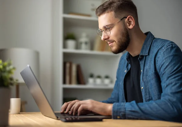 Genç sakallı adam bilgisayarla evden çalışıyor. Uzaktan kumandalı.