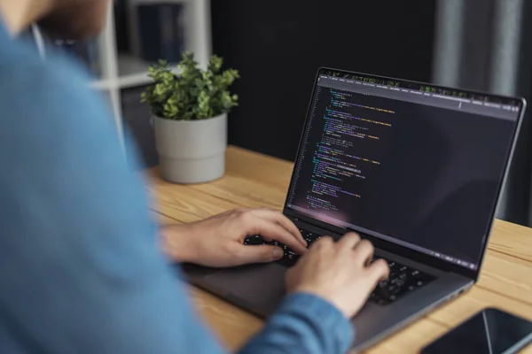 Programcı dizüstü bilgisayarda kodlama yapıyor, yenilik yazılımı üzerinde çalışıyor.