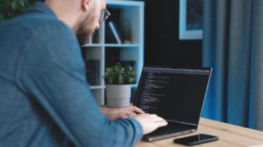 Kot gömlekli sakallı adam. Kod yazıyor. Laptop kullanıyor.