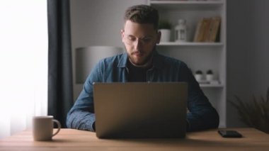 Laptopta yazan yakışıklı sakallı adam, genç kodlayıcı yazma kodu, içerisi aydınlık olan ev ofisi.
