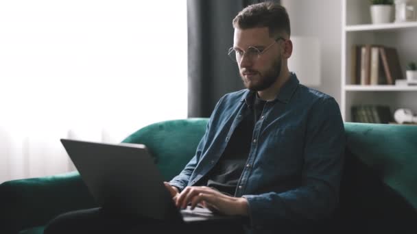 Kot Gömlekli Sakallı Genç Adam Dizüstü Bilgisayarda Çalışıyor Kanepede Oturan — Stok video