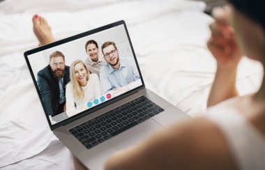 Yatakta oturan genç bir kadın, evdeki dizüstü bilgisayarında ofisten proje ekibiyle video görüşmesi yapıyor. Olgun bir bayanın dizüstü bilgisayarla sohbet etmesi, arkadaşlarıyla ya da aileleriyle konuşması.