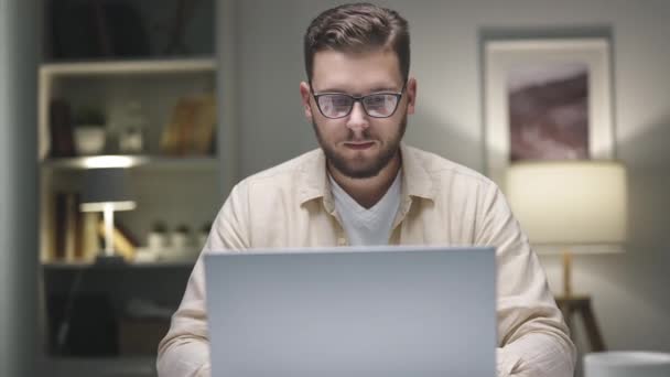 年轻的高加索男子在家里工作 桌上拿着笔记本电脑和电话 — 图库视频影像