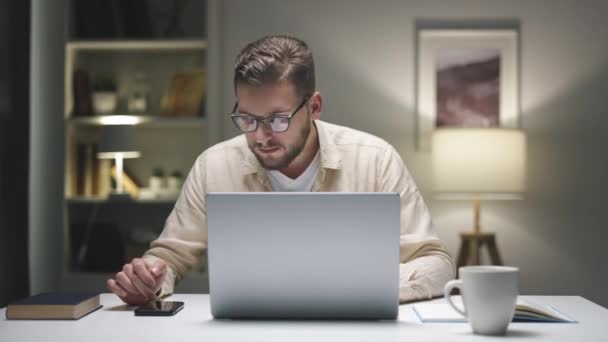 Człowiek Pracujący Nocy Laptopie Domu Przewijający Smartfona Płacący Rachunki Online — Wideo stockowe