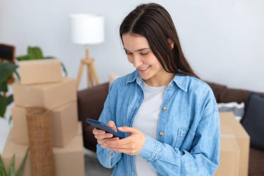 Yeni bir eve taşınmak, kiralık konutlar. Yeni bir eve taşınmak için bir ulaşım şirketi ve nakliyecileri aramak ve sipariş etmek için cep telefonu kullanan mutlu beyaz bir kadın.