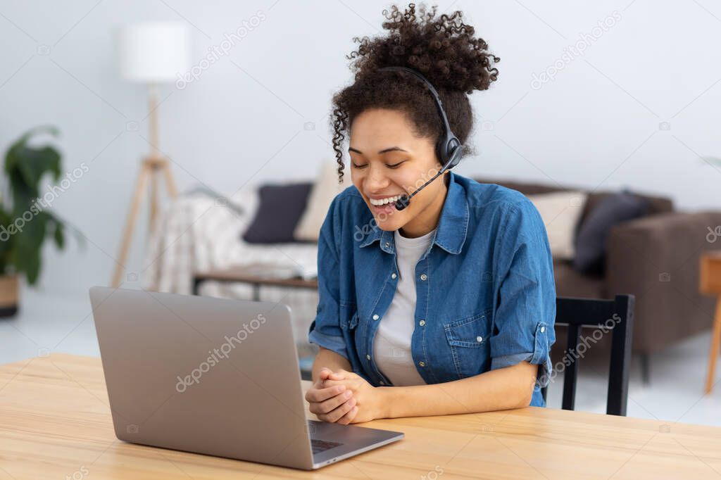 Portrait of happy African American female employee customer support services in headset sitting in modern office, online consultation. Woman call center. Female customer support or sales agent