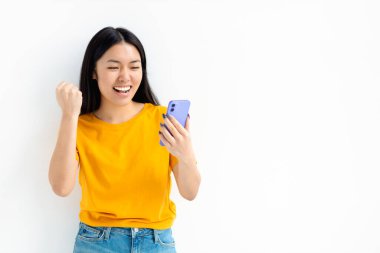 Cep telefonu tutan neşeli bir Asyalı kadının portresi ve beyaz arka planda duran ekrana bakması.