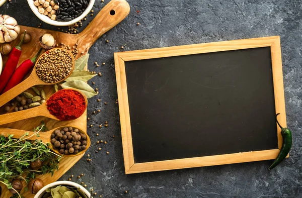 Food menu concept. Chalkboard with spices and herbs top view with rice, various beans on dark background
