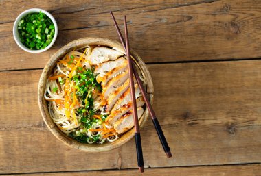 Kızarmış tavuk göğsü ve ahşap arka planda sebzeli Ramen eriştesi, üst manzara. Lezzetli Asya tarzı öğle yemeği ya da akşam yemeği