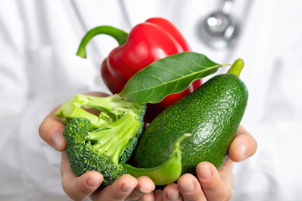 Healthy food concept. Nutritionist doctor holds fresh broccoli, avocado and peppers in his hands