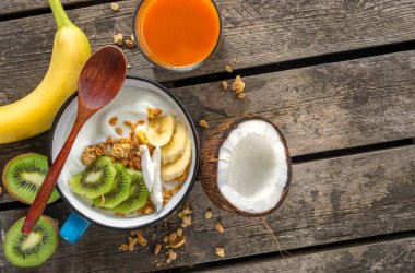 Tahıllı hindistan cevizli yoğurt ve kırsal ahşap masa üzerinde meyve ve fotokopi alanı. Sağlıklı vejetaryen kahvaltı konsepti