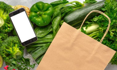 İnternetten yemek sipariş et. Boş ekranlı cep telefonu, kese kağıdı ve yeşil sebzeli. Sağlıklı yiyecekler alın.