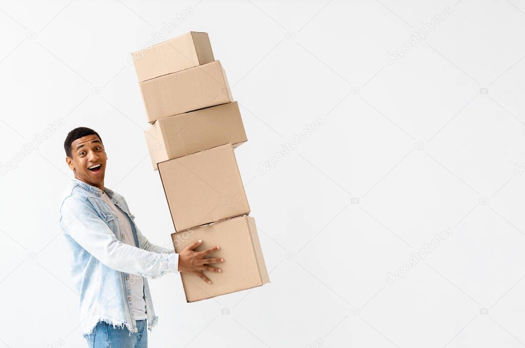 Moving concept. Young happy African American man with stack of cardboard boxes on white background, copy space