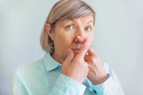 Verlies van geur. Senior vrouw raakt haar neus met haar vingers vanwege het verlies van haar reukzin. Zelfdiagnose covid-19. Symptomen van het coronavirus — Stockfoto