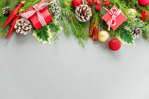 Gri arka planda noel kompozisyonu düz çizgi. Yaratıcı noel hediyeleri, kırmızı ve altın, köknar dalları ve kırmızı böğürtlen. Noel, yeni yıl konsepti, kış
