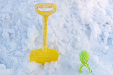 Children's Games with snow. Snow shovel and snowball covered with frost on snowy area. Winter activities