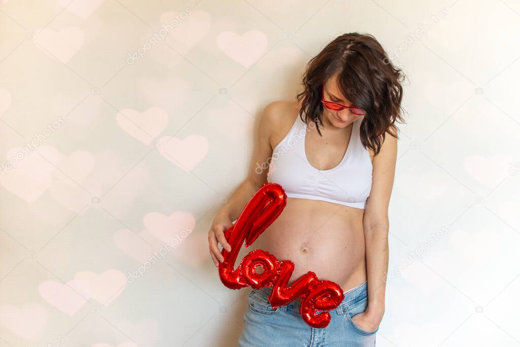 Happy valentines day pregnancy. Pregnant on Valentines Day with a love ball and in pink glasses on a light background. Love and pregnancy concept
