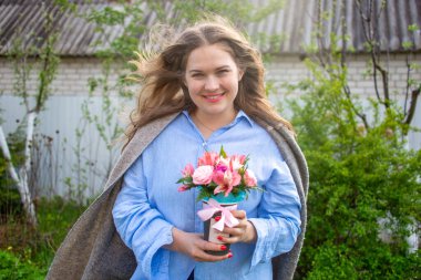 Açık havada elinde bir buket çiçekle gülümseyen güzel bir kız. İlkbahar, 8 Mart, 14 Şubat, melodram, aşk
