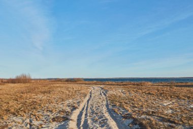 Göl kıyısındaki plajda mavi gökyüzü ve bulutlu Ukrayna kırsal manzara yolu.