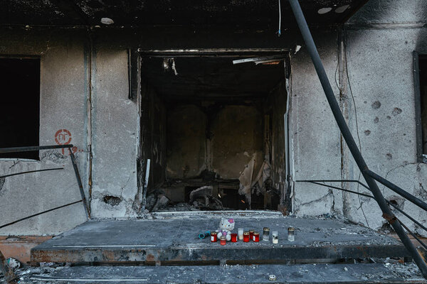 Ukraine, Borodyanka, 30 April 2022: a burned-out building near which children's toys lie and candles stand