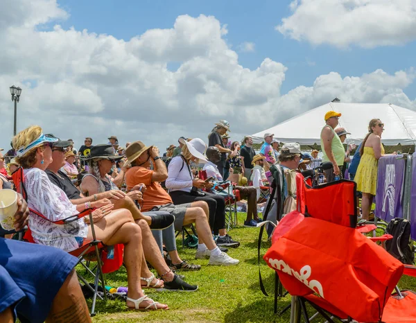 NEW ORLEANS, LA, USA - APRIL 23, 2022: Diverse crowd standing and seated in folding chairs at free French Quarter Festival in Woldenberg Park