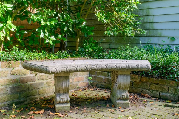 Closeup of concrete garden bench on brick patio of historic New Orleans home