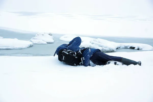Un homme vêtu d'une veste bleue se trouve dans la neige près d'une baie gelée, un photographe essaie sur un cadre, une vue de dos — Photo