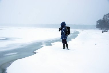Erimiş buzla kaplı kışın beyaz manzarası. Fotoğrafçı kıyıda duruyor..