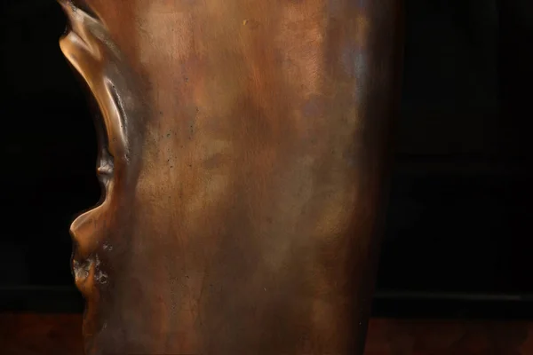 Un morceau de sculpture en bronze poli avec un bord dentelé à gauche — Photo