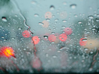 Yağmurlu bir günde arabanın ön camına yağmurun seçici odak noktası. Sürücünün bakış açısı.