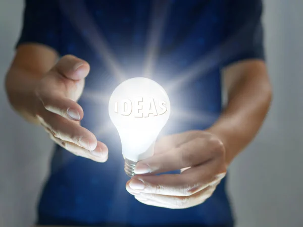 Man holding bright shining light bulb represents a new idea, thought, invention, innovation, solution, creativity, technology, and business. Creative ideas concept