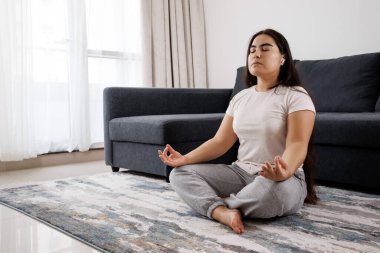 Çekici genç bir kadın spor salonundaki kanepede meditasyon yapıyor, rahatlıyor ve egzersiz yapıyor. Sağlık ve rahatlama kavramı