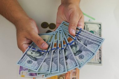 Adam beyaz arka planda bir yığın dolar tutuyor.