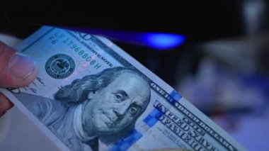100 dolarlık banknotu para dedektörüyle inceliyorum. Detektif banknotları.